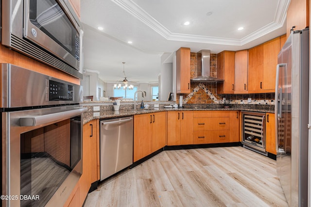 kitchen with wine cooler, wall chimney exhaust hood, sink, appliances with stainless steel finishes, and dark stone counters