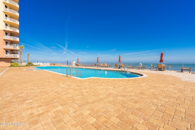 view of swimming pool featuring a water view and a patio area