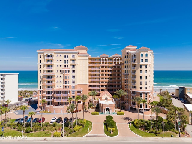 view of building exterior featuring a water view and a beach view