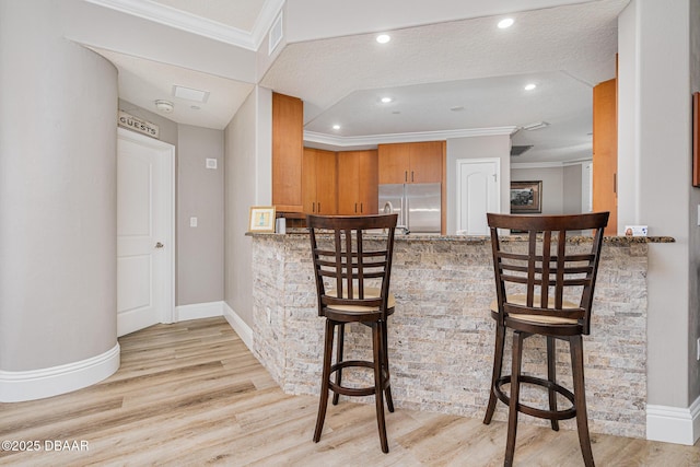 kitchen featuring light hardwood / wood-style flooring, stainless steel fridge, a kitchen bar, and kitchen peninsula