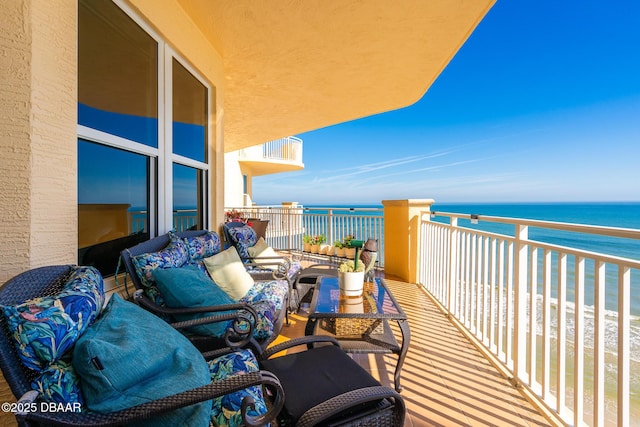 balcony featuring a view of the beach and a water view