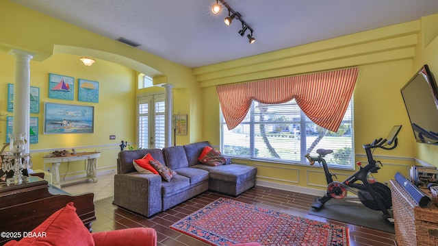 living area featuring arched walkways, visible vents, a healthy amount of sunlight, and ornate columns