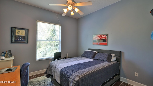 bedroom with dark tile patterned floors, a ceiling fan, and baseboards