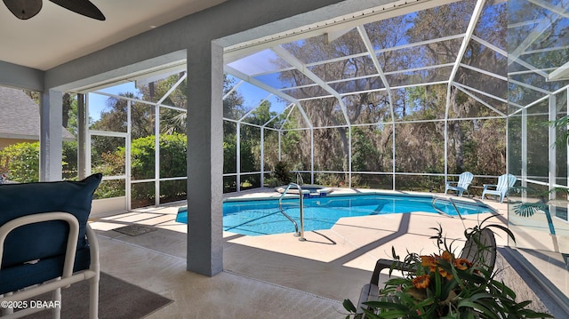 pool with glass enclosure, a ceiling fan, and a patio