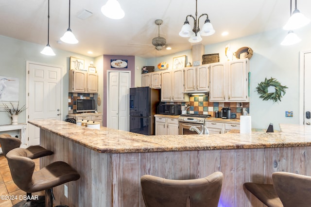 kitchen with a kitchen bar, black appliances, light stone counters, and tasteful backsplash