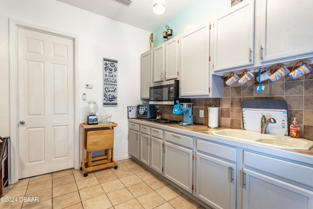 kitchen with stainless steel appliances, decorative backsplash, light tile patterned floors, sink, and white cabinetry