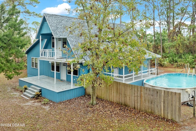 rear view of property with a balcony and a pool side deck