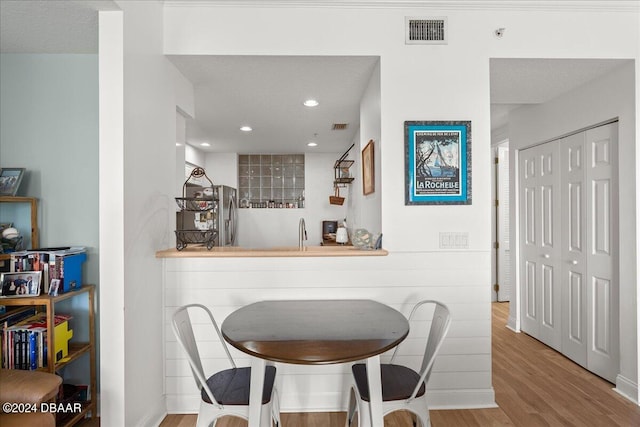 dining room featuring a textured ceiling, light hardwood / wood-style flooring, and indoor bar