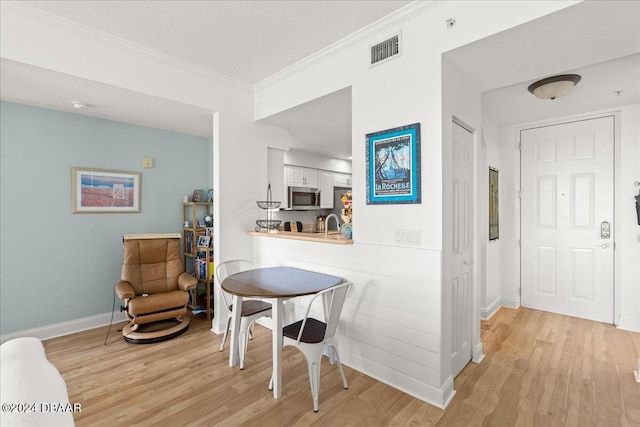 interior space featuring light hardwood / wood-style flooring, a textured ceiling, and crown molding