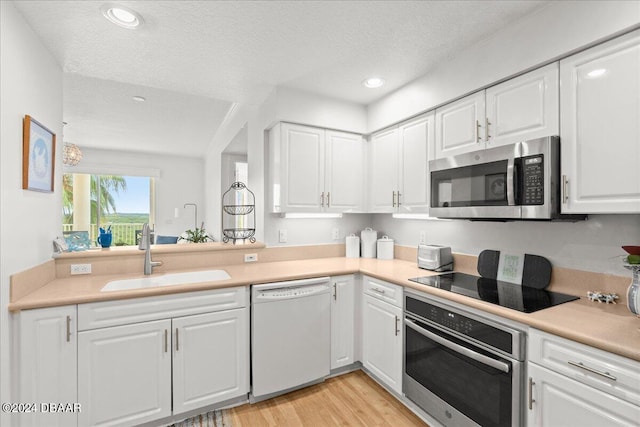 kitchen with white cabinets, a textured ceiling, sink, and appliances with stainless steel finishes