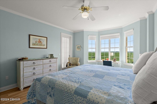 bedroom featuring a textured ceiling, hardwood / wood-style flooring, ceiling fan, and crown molding