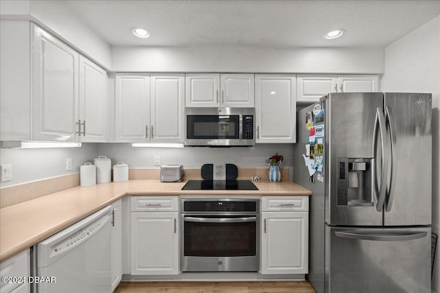 kitchen with white cabinetry, light hardwood / wood-style floors, appliances with stainless steel finishes, and a textured ceiling