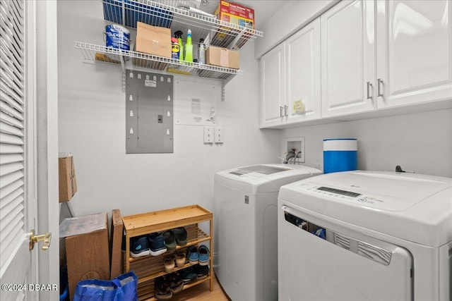 washroom featuring cabinets, washing machine and dryer, electric panel, and hardwood / wood-style flooring