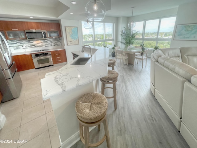 kitchen with a breakfast bar, sink, pendant lighting, and appliances with stainless steel finishes