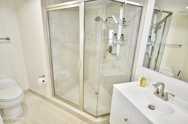 bathroom featuring toilet, vanity, tile patterned flooring, and a shower with door