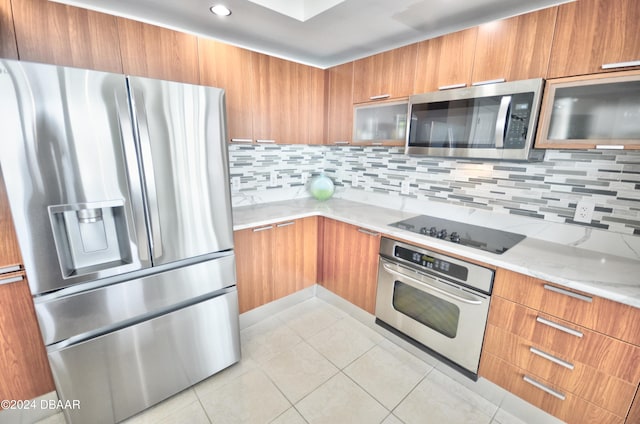 kitchen with backsplash, appliances with stainless steel finishes, light tile patterned floors, and light stone countertops