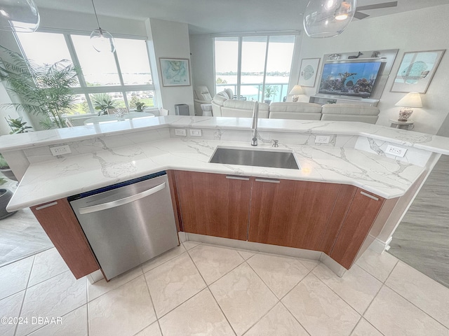 kitchen featuring light stone counters, dishwasher, sink, light tile patterned floors, and decorative light fixtures