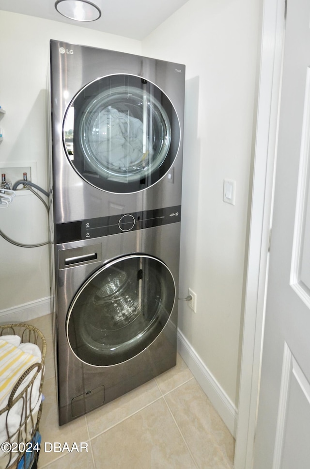 clothes washing area featuring light tile patterned floors and stacked washer and dryer