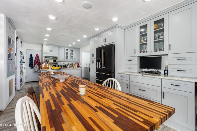 kitchen with gray cabinets, stainless steel oven, light stone counters, and high end refrigerator