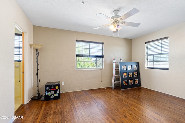 unfurnished room with a wealth of natural light, ceiling fan, dark wood-type flooring, and a textured ceiling