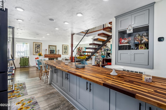 bar featuring butcher block countertops, gray cabinetry, dark wood-type flooring, and a textured ceiling