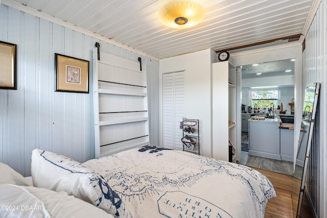 bedroom featuring wood-type flooring, a barn door, a closet, and wood walls