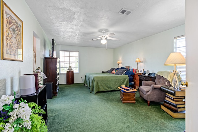 carpeted bedroom with ceiling fan, a textured ceiling, and multiple windows