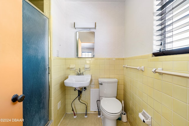 bathroom featuring sink, tile walls, and toilet