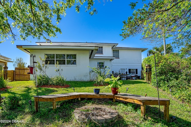 back of property with an outdoor fire pit and a lawn