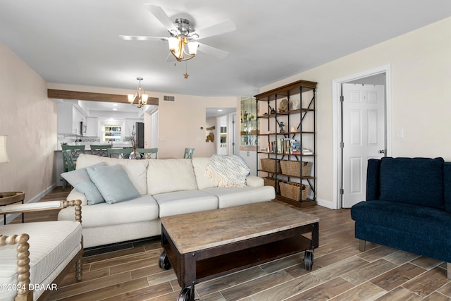 living room with wood-type flooring and ceiling fan with notable chandelier