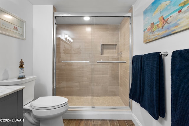 bathroom featuring wood-type flooring, vanity, toilet, and a shower with door