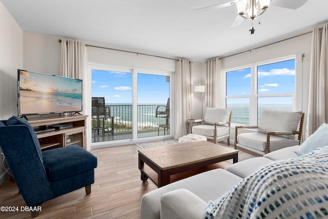 living room featuring ceiling fan, light hardwood / wood-style floors, and a water view