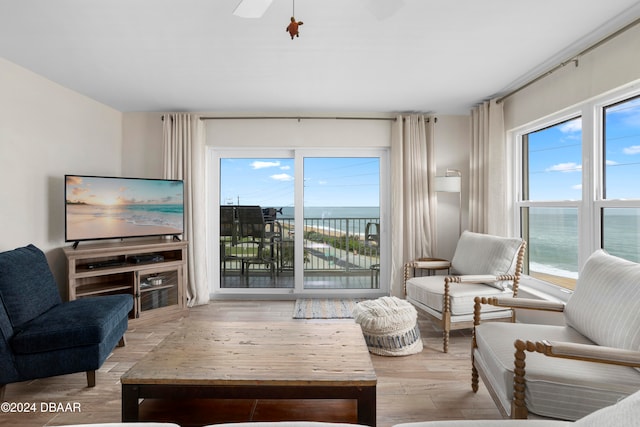 living room featuring a water view, ceiling fan, a healthy amount of sunlight, and light hardwood / wood-style floors