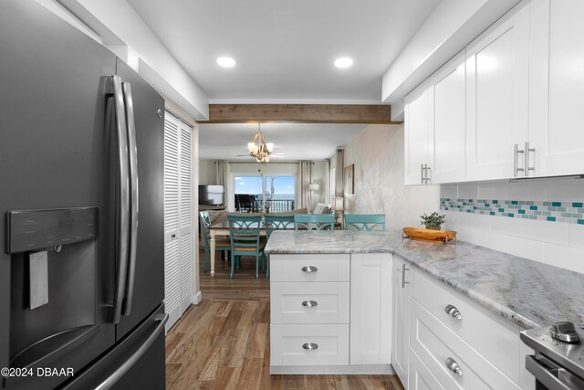 kitchen with kitchen peninsula, stainless steel fridge, light stone countertops, hardwood / wood-style flooring, and white cabinetry