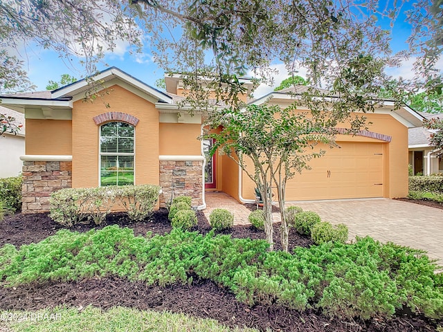 645 Elk River Dr, Ormond Beach, FL 32174 - view of front of house featuring stone siding, stucco siding, an attached garage, and decorative driveway