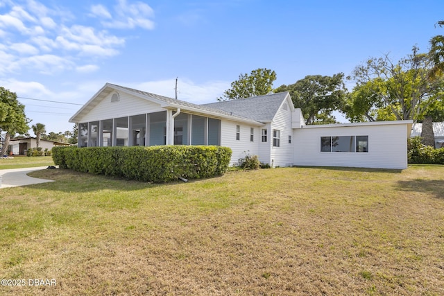 back of house with a sunroom, a lawn, and a shingled roof
