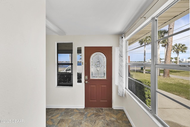 entrance foyer featuring stone finish flooring, a wealth of natural light, and baseboards