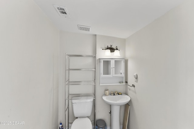 bathroom featuring visible vents, toilet, and a sink