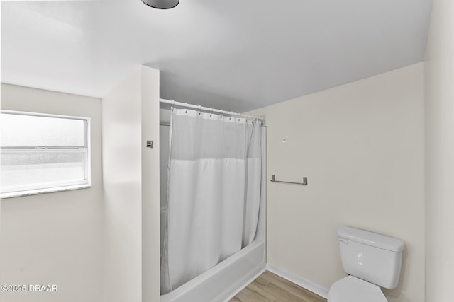 bathroom featuring baseboards, wood finished floors, shower / bath combination with curtain, and toilet