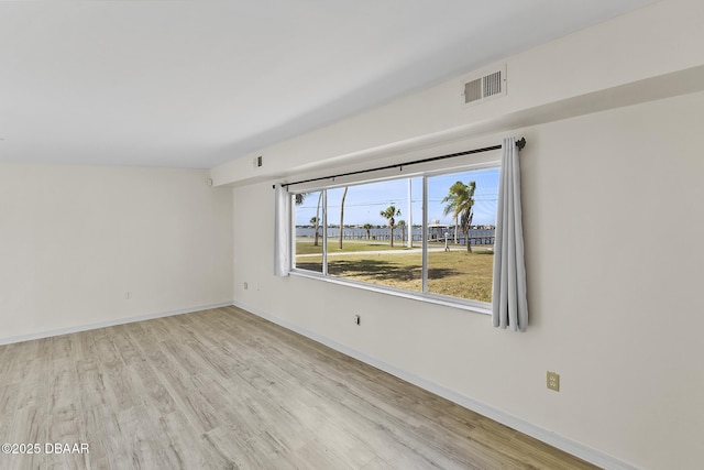 spare room featuring visible vents, light wood-type flooring, and baseboards