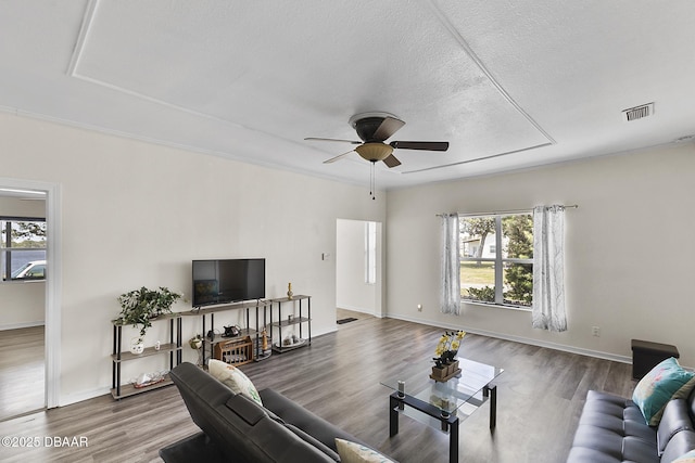 living room with visible vents, wood finished floors, ceiling fan, and plenty of natural light