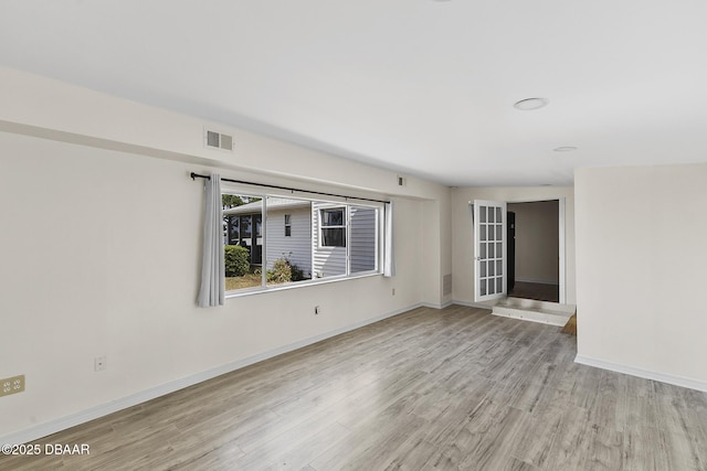 empty room with visible vents, light wood-style flooring, and baseboards