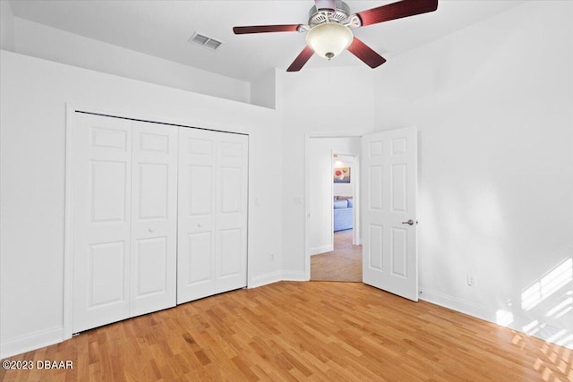 unfurnished bedroom featuring light wood-type flooring, ceiling fan, and a closet