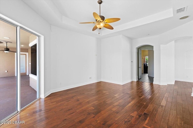 empty room featuring ceiling fan, wood-type flooring, and a raised ceiling