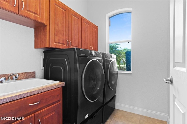 washroom with cabinets, light tile patterned flooring, separate washer and dryer, and sink