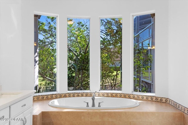 bathroom featuring a wealth of natural light, vanity, and tiled bath