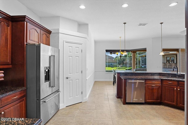 kitchen with stainless steel appliances, sink, a textured ceiling, a chandelier, and pendant lighting