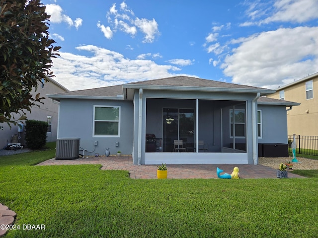 rear view of house with central AC unit, a sunroom, and a yard