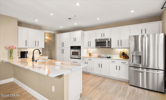 kitchen with sink, stainless steel appliances, light hardwood / wood-style flooring, kitchen peninsula, and white cabinets