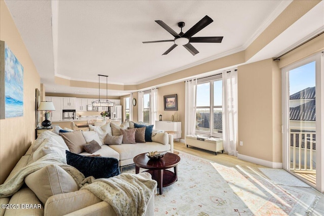 living room featuring light wood-type flooring, ceiling fan, and ornamental molding